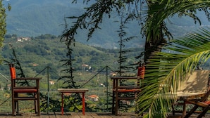 A wooden deck with chairs and a table overlooking a mountainous landscape. - Villa Pedone - Historic house with private pool for holiday rental in the hills of Lucca, Tuscany. (San Concordio Di Moriano)