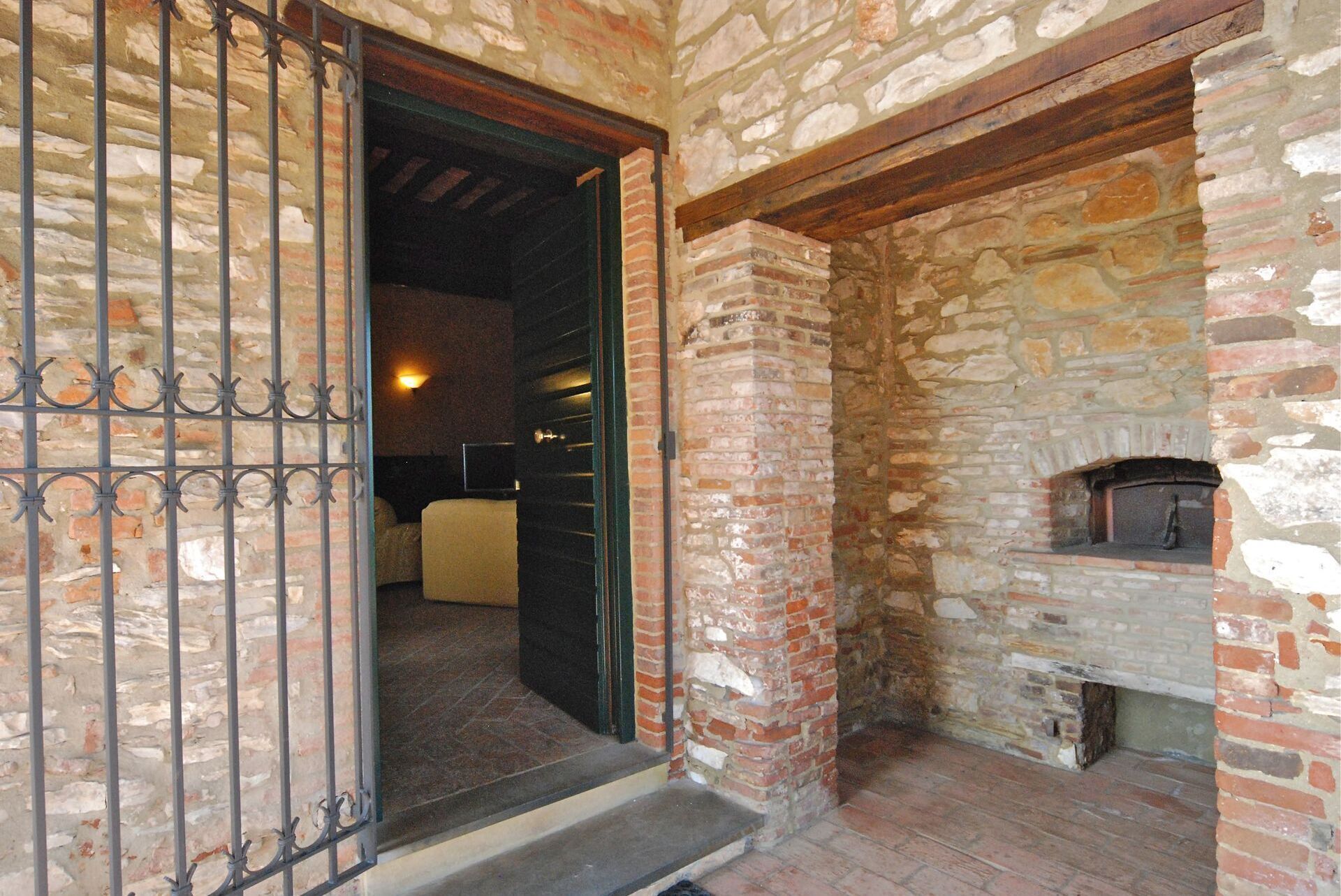 A stone-walled room with a fireplace, a bed, and a metal gate.