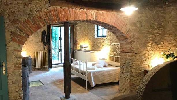 A rustic bedroom with a stone archway, a bed, a small table, and a radiator. - Stunning private villa with private pool, A/C, internet, TV, patio, panoramic view, close to Lucca (Vicopelago)