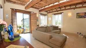 A cozy living room with a sofa, wooden beams on the ceiling, and a view through a glass door to the outside. - Stunning private villa with private pool, A/C, internet, TV, patio, panoramic view, close to Lucca (Vicopelago)