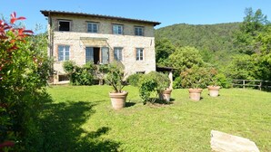 A stone house with a tiled roof, surrounded by a well-maintained garden with potted plants and a grassy lawn. - Stunning private villa with private pool, A/C, internet, TV, patio, panoramic view, close to Lucca (Vicopelago)