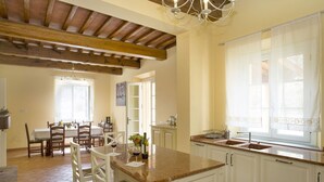 Une cuisine spacieuse avec des armoires blanches, un comptoir en granit et un plafond en bois.