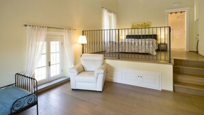 Une chambre à coucher avec un lit, une chaise, un escalier et une fenêtre avec des rideaux.