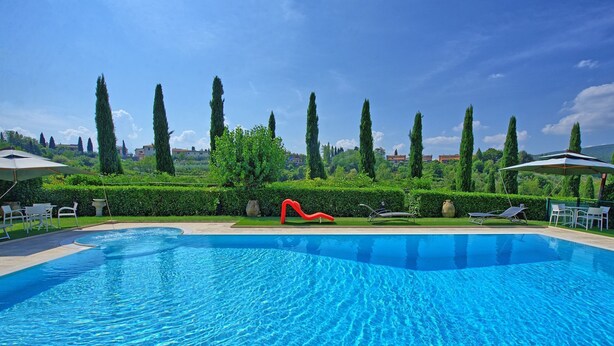 A swimming pool with a red slide, surrounded by neatly trimmed hedges and tall trees. - Beautiful apartment for 2 guests with pool, A/C, WIFI, TV and panoramic view (San Gimignano)