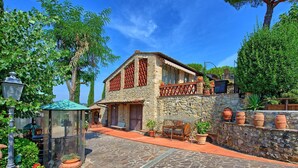 Una casa in pietra con tetto in tegole, un balcone e un muro di pietra con vasi di piante.