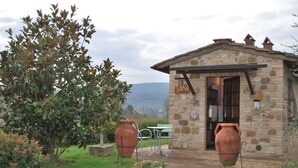 A stone building with a door and windows, surrounded by greenery and two large pots. - Nice apartment for 2 guests with A/C, WIFI, pool, TV and panoramic view (San Gimignano)
