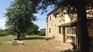A stone building with a garden and a lounge chair.
