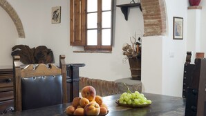 Un comedor rústico con una mesa de madera, un bol de melocotones y un bol de uvas verdes.