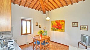 A cozy kitchen with a dining table, chairs, a coffee maker, and a TV. - Vittoriana 3 - Apartment with pool (San Gimignano)