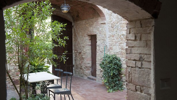 An outdoor patio area with a stone archway, a table, and chairs.