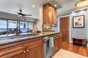 A modern kitchen with wooden cabinets, a stainless steel dishwasher, and a ceiling fan.