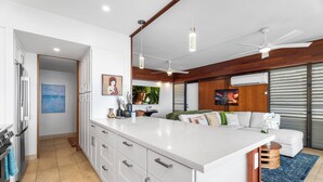 Une cuisine moderne avec des meubles blancs, un grand îlot central et un ventilateur de plafond.