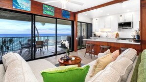Een moderne woonkamer met een grote schuifpui die uitkomt op een balkon met uitzicht op de oceaan.