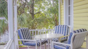 A covered porch with white furniture, including two chairs and a table. - HISTORIC DISTRICT ~ Walk Everywhere ~ Private Parking! (St. Augustine)