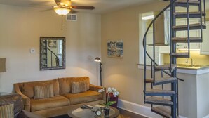 A spacious living room with a high ceiling, a built-in staircase, a sofa set, a coffee table, and a small round rug. - HISTORIC DISTRICT ~ Walk Everywhere ~ Private Parking! (St. Augustine)