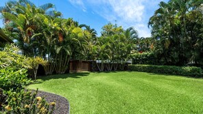 Un jardin bien entretenu, agrémenté de diverses plantes tropicales et d’une pelouse parfaitement taillée.