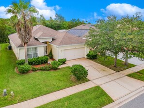 A residential house with a sloped roof, a garage, and a well-maintained lawn. - Lovely Pool Home, Pets considered. Orlando 1744 (Orlando)
