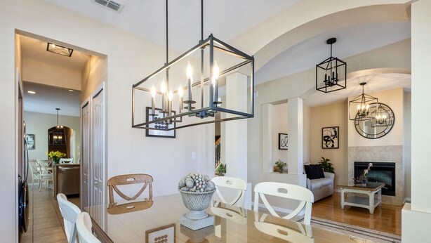 Una sala de estar moderna con una mesa de comedor de vidrio, sillas blancas y una chimenea.