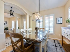 A dining area with a glass table, wooden chairs, and a modern pendant light.