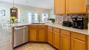 Una cocina moderna con armarios de madera, lavavajillas, tostadora y cafetera.