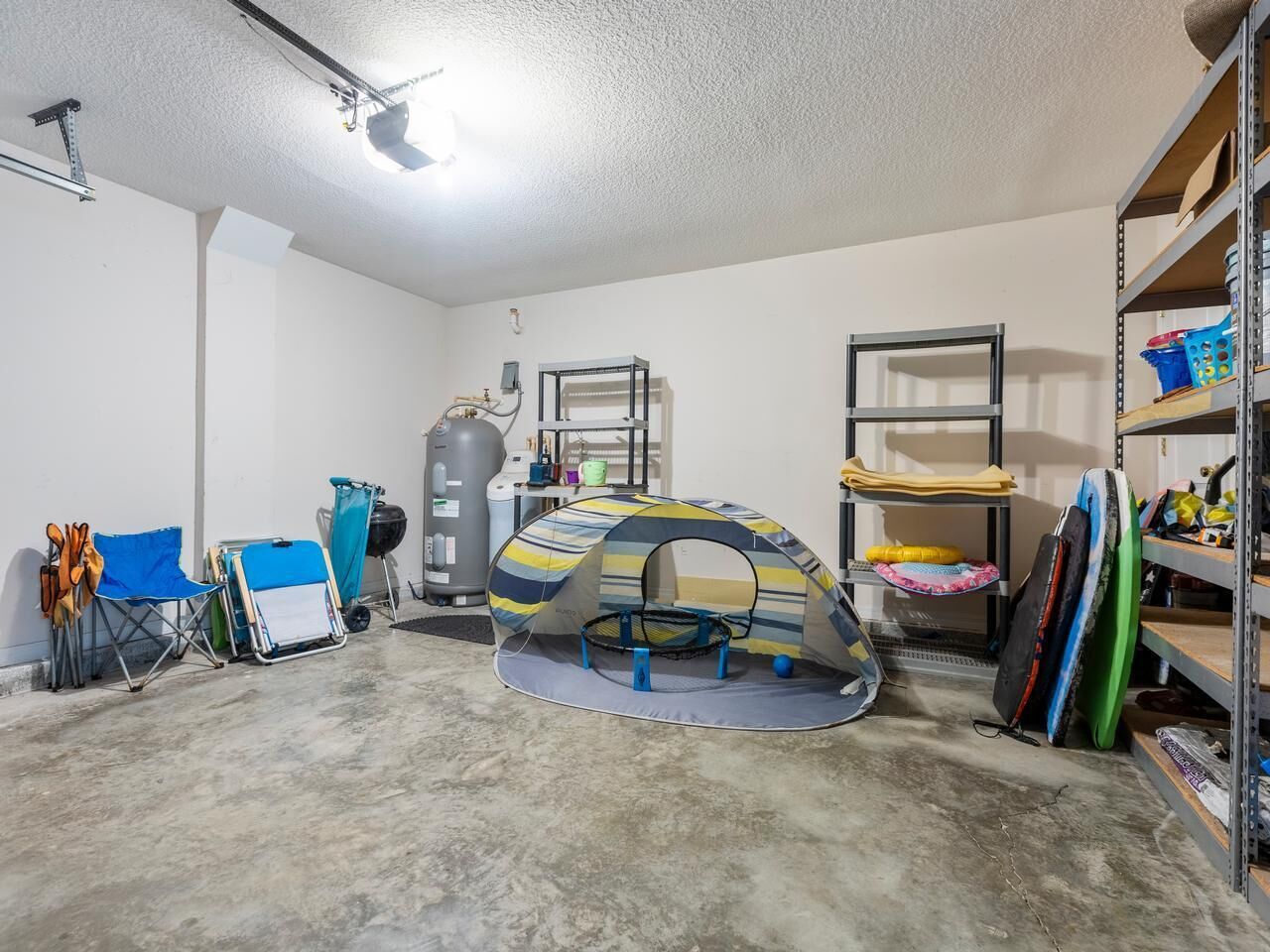 A garage with a trampoline, shelves with various items, and a tent.