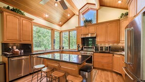 Een moderne keuken met houten kasten, roestvrijstalen apparatuur en een groot eiland met barkrukken.