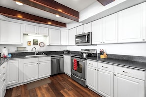 Enjoy cooking in this well-equipped kitchen with a stainless steel range, microwave, and granite countertop.