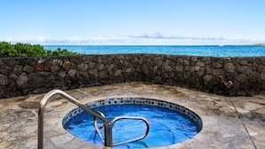 Ein Whirlpool mit Steinwand und Blick auf den Ozean.