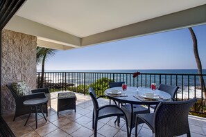 A terrace with a table set for two, overlooking a beach with the ocean in the background. - 🏖️Direct Ocean Front | Steps from the Beach | Large Lanai (Kailua Kona)