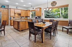 A kitchen with wooden cabinets, a central island, and a dining area with a wooden table and chairs.