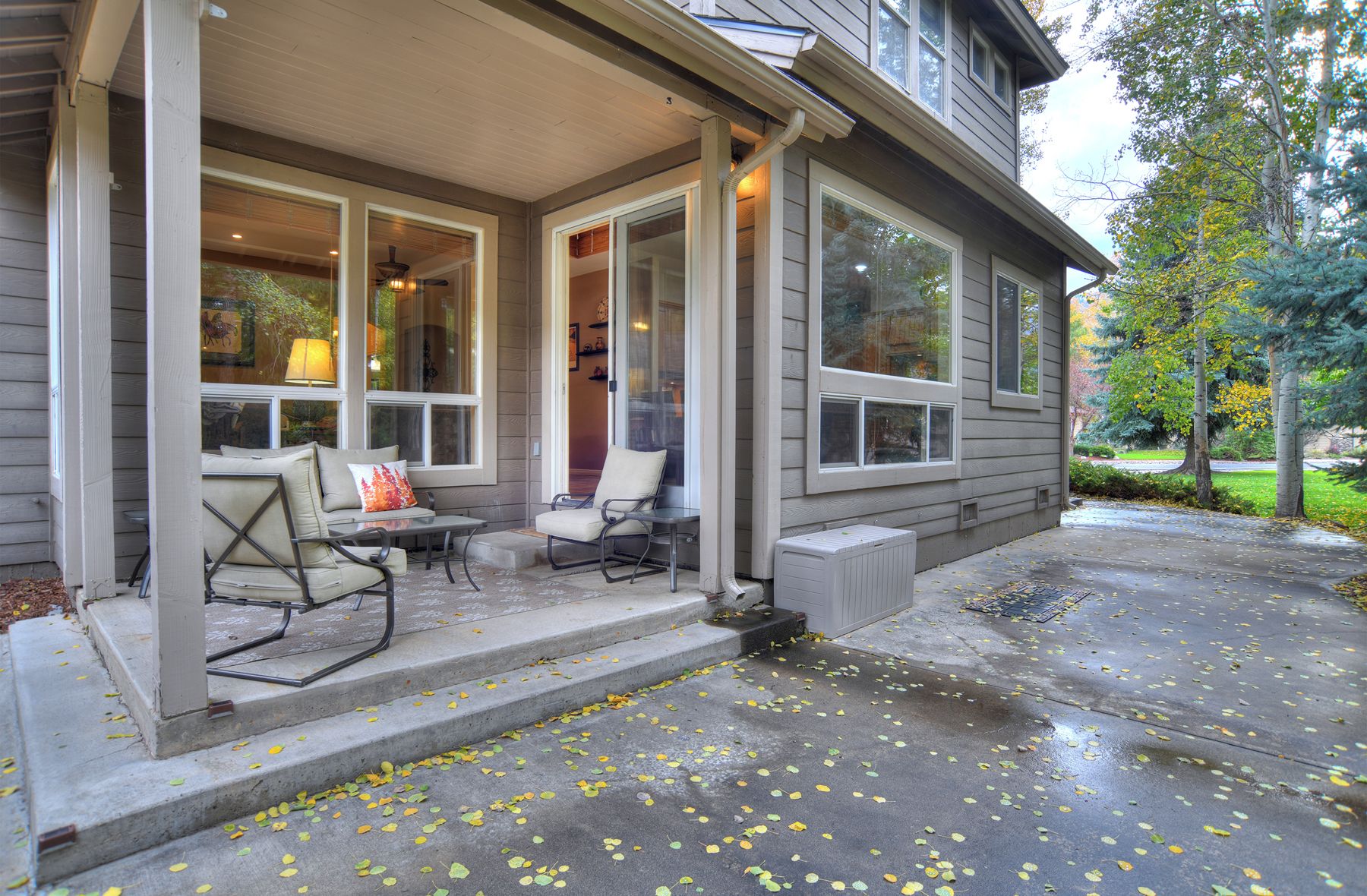A covered porch with outdoor seating, a radiator, and a tree in the background.