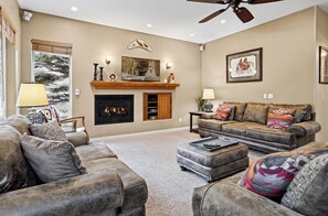 A living room with a fireplace, leather sofas, and a ceiling fan.