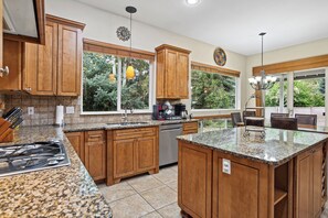 A kitchen with wooden cabinets, granite countertops, a built-in dishwasher, and a large island.