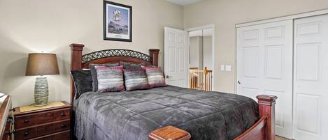 A bedroom with a bed, a nightstand, a lamp, a framed picture on the wall, and a ceiling fan.