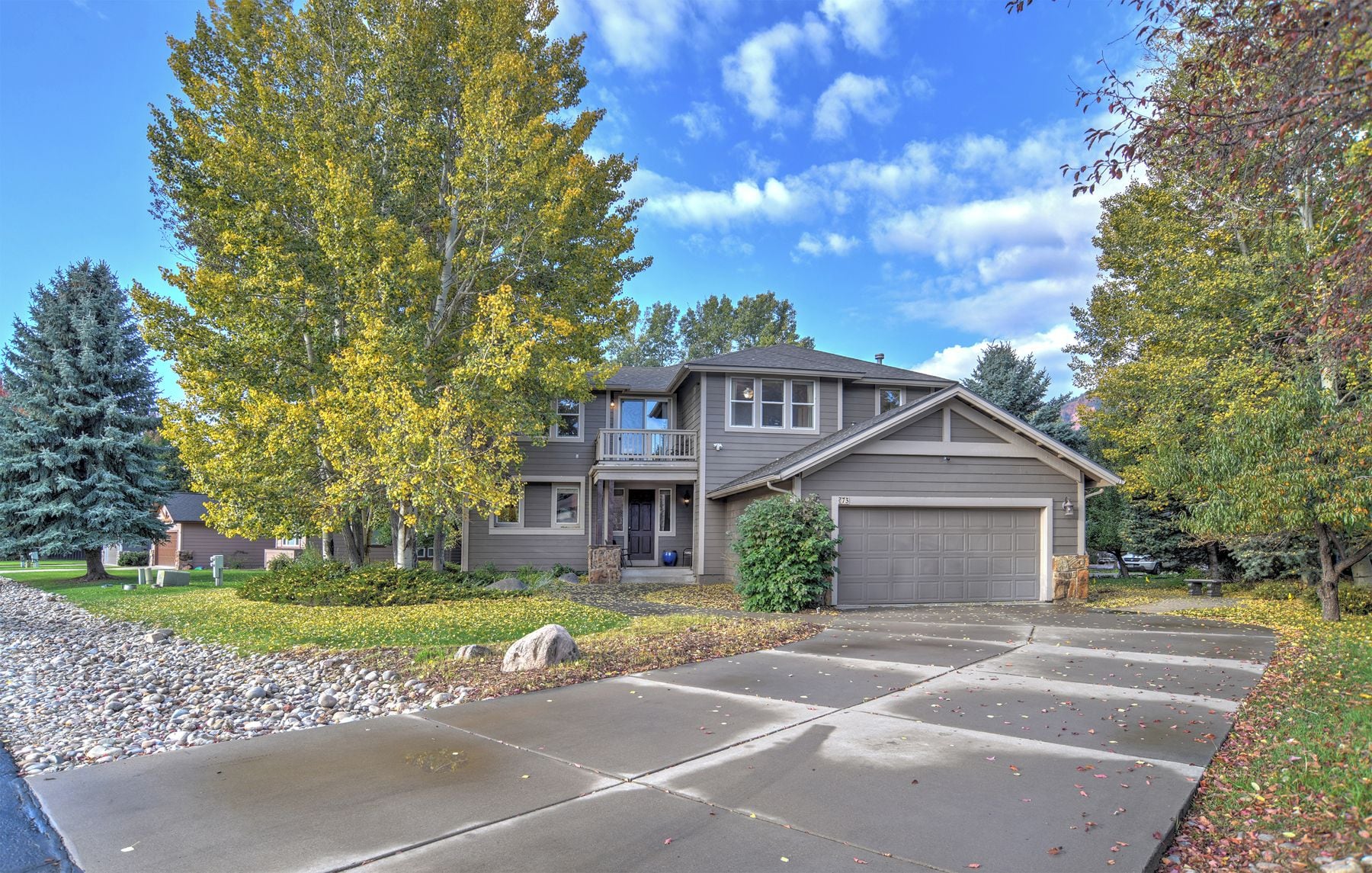 A two-story house with a garage, surrounded by trees and a well-maintained lawn.