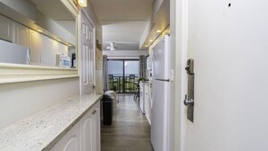 A narrow kitchen with white cabinets, a granite countertop, and a view to a balcony. - Million Dollar Views ~ Heated Pool ~ King Bed (St Augustine)