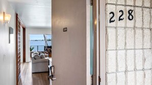 Un pasillo con un letrero del número 228, un sofá y vista al mar.