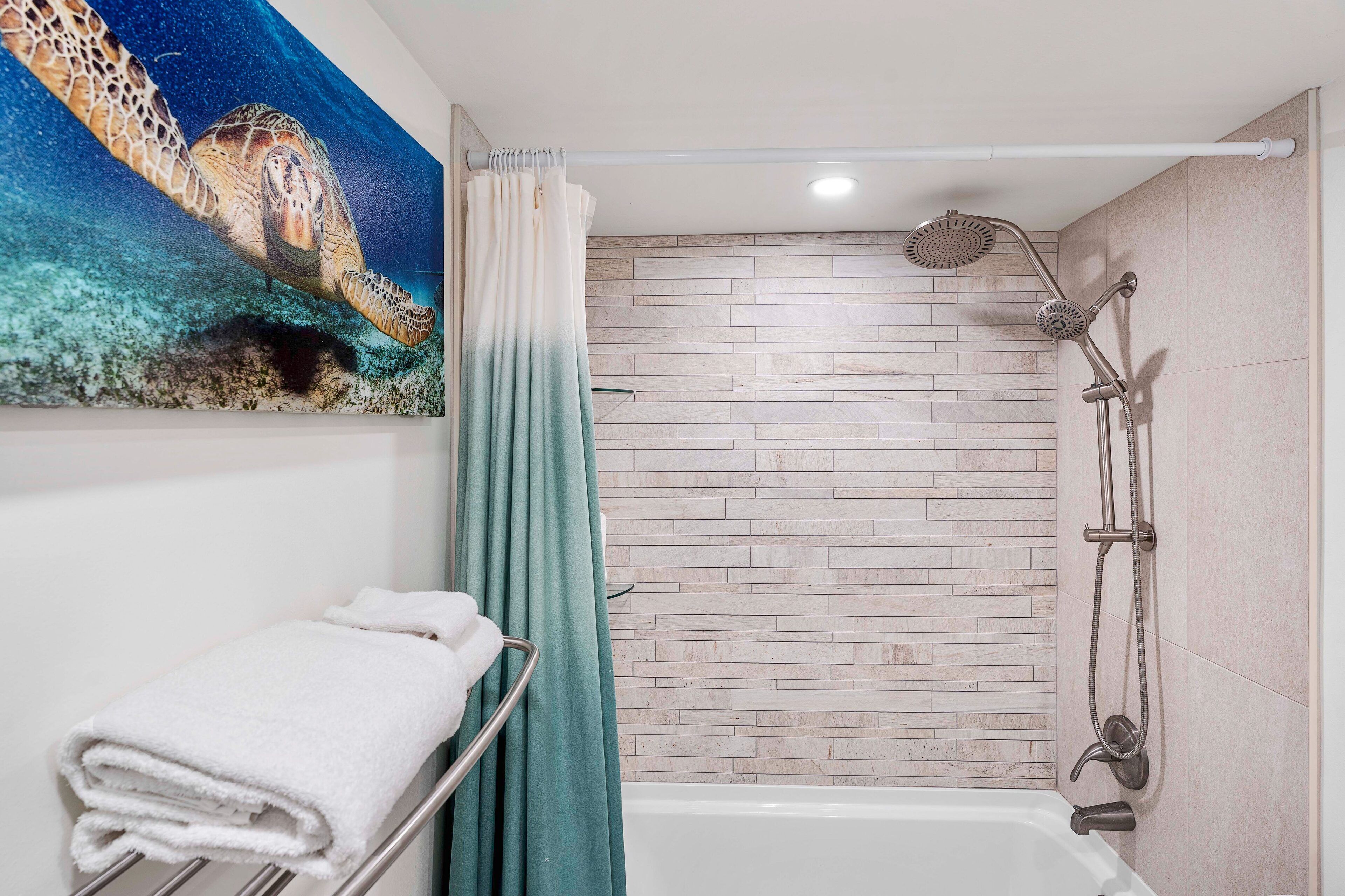 A bathroom with a shower, a towel rack, and a wall-mounted painting of a sea turtle.
