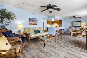 A living room with wicker furniture, a glass coffee table, and a ceiling fan. - 🏖️Across from Magic Sands Beach | 2BR Kona Condo w/ AC & Ocean View (Kailua Kona)