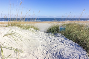 Ein sandiger Strand mit Fußspuren und hohem Gras.