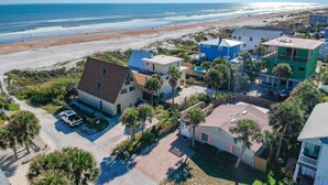 Luchtbeeld van een kustgebied met woningen, een strand en een heldere lucht.