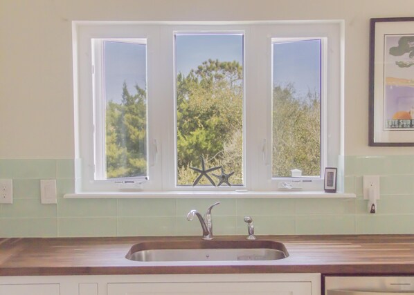 A kitchen with a window above a sink, a starfish decoration, and a framed picture on the wall.