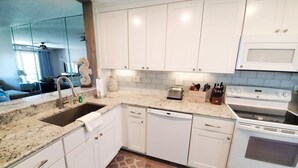 A kitchen with white cabinets, a granite countertop, a dishwasher, a stove, and a toaster. - Sea Place 13239:  Charming Beach Condo: 2 Bedrooms, Pools & Tennis Courts (St. Augustine)