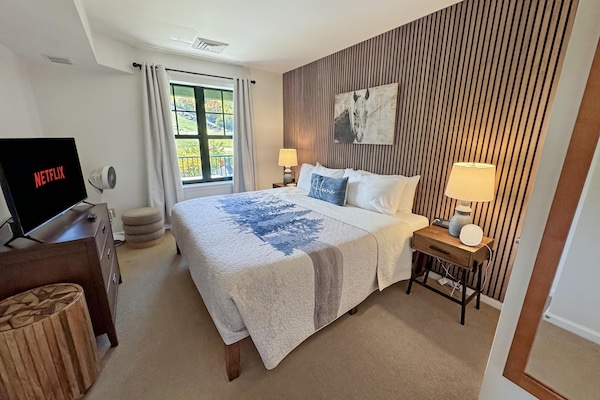 Bright, cozy king bedroom with modern wood accent wall and mountain front views