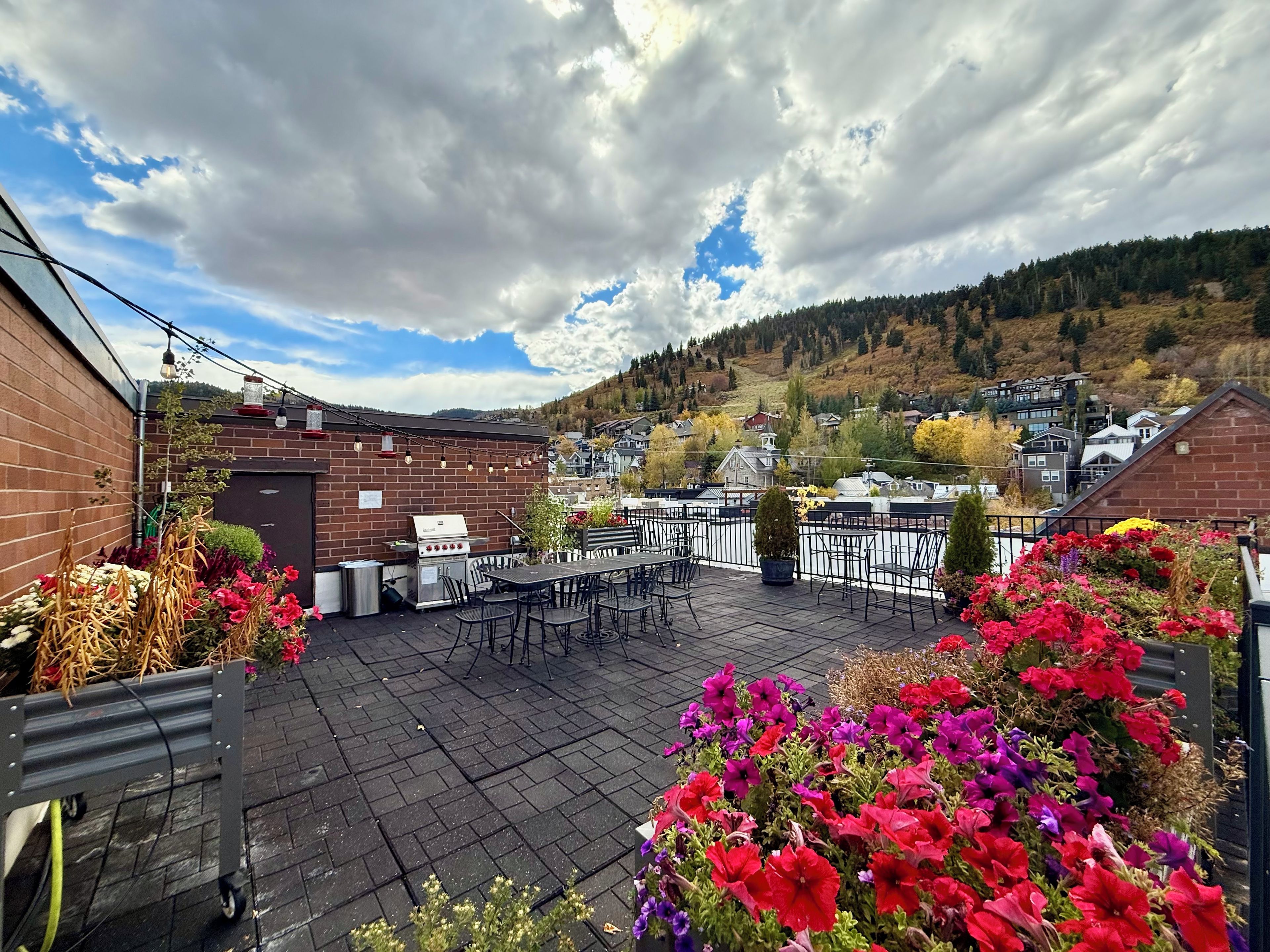 An outdoor patio with a grill, seating area, and flower beds.