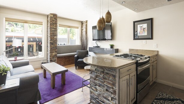 A modern kitchen with a stone island, built-in oven, and a flat-screen TV. - Managed by Park City Lodging-On Main Street-Walk to Lift-Rooftop Deck-Views (Park City)