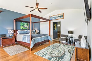 A bedroom with a four-poster bed, a ceiling fan, a TV, a desk, and a chair.