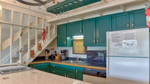 Une cuisine avec des armoires de couleur turquoise, un réfrigérateur en acier inoxydable, un four à micro-ondes et un lave-vaisselle.