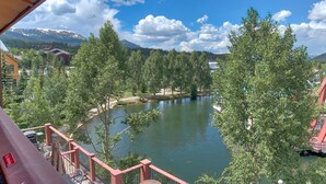 Une vue d’un lac entouré d’arbres et de montagnes, avec un bâtiment en arrière-plan.
