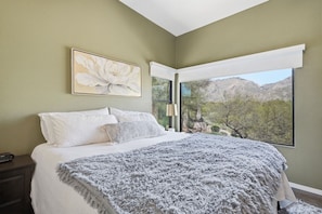 Una camera da letto con un letto grande, vista sulle montagne e un quadro appeso al muro.